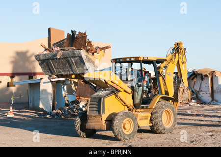 A backhoe is being used to remove debris from the demolition of  an old commercial building. Stock Photo