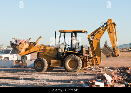 A backhoe is being used to remove debris from the demolition of  an old commercial building. Stock Photo