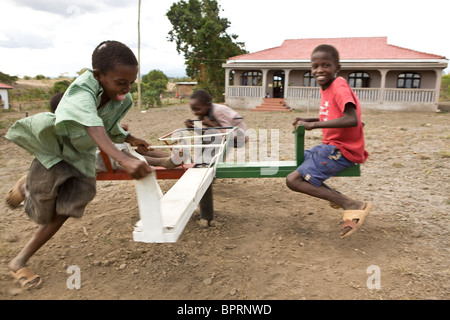 African children play on a merry-go-round in an orphanage in Kilimanjaro, Tanzania. Stock Photo