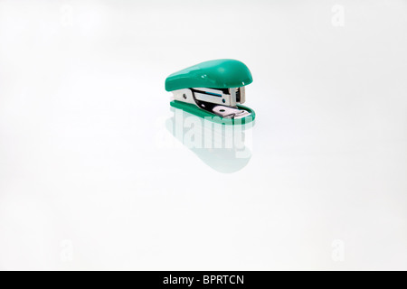 Open green plastic stapler on reflective background background Stock Photo