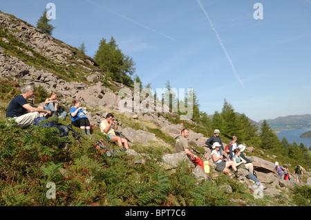 Group of walkers resting at Old Burtness on their way up Red Pike on a sunny day under  a blue sky with Crummock Water behind. Stock Photo