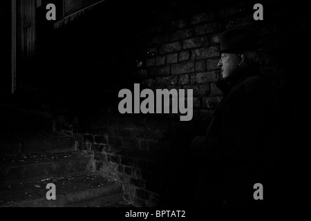 Film Noir depicting a quiet and dangerous man waiting in a darkened alley. Stock Photo