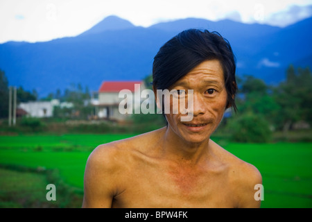 Portrait of Vietnamese Farmer in front of rice paddies, Central Vietnam. Indochina. Southeast Asia. January 2010. Stock Photo