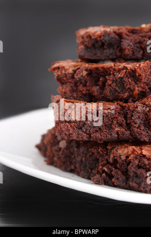 Pile of chocolate fudge brownies on a plate with a grey background (short depth of field) Stock Photo
