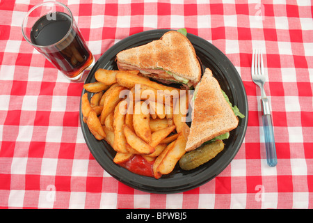 A plate of a bacon, lettuce and tomato sandwich also known as the BLT , french fried potato wedges, a pickle and catsup Stock Photo