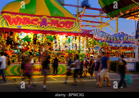 Blurred crowd at whac-a-mole booth on the Midway at dusk during the Toronto CNE fair Stock Photo