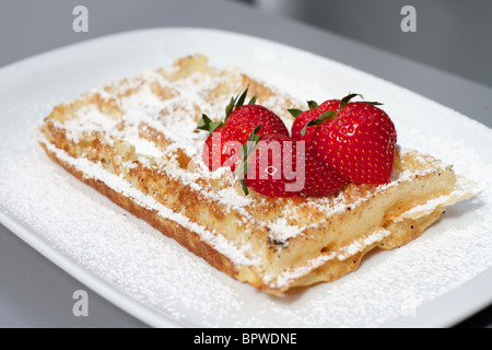 Classic Belgian Waffle with a dusting of icing sugar and red strawberries Stock Photo