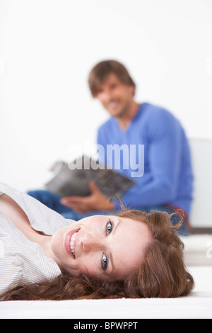 Woman lying on rug, man reading Stock Photo