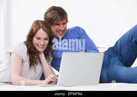 Couple relaxing on rug using a laptop Stock Photo