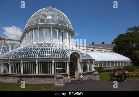 Ireland, Northern, Belfast, Botanic Gardens with people sat on benches outside the Palm House next to Queens University. Stock Photo