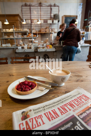 Detail of coffee ,cake, and local newspaper in traditional bakers shop and cafe in central Antwerp in Belgium Stock Photo