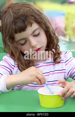 brunette little girl eating summer ice cream color spoon