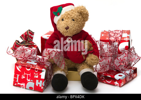Christmas Teddy bear. Much loved child's teddy dressed as Santa sitting among gaily wrapped presents. Stock Photo