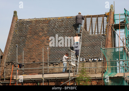 Builders working on the roof of an old building in the U.K. Stock Photo