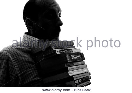 Silhouetted man carrying books Stock Photo