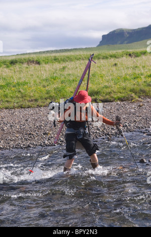 A woman skier crossing a river on Umnak Island in the Aleutian Islands. Stock Photo