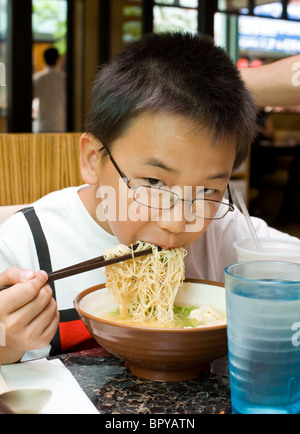 Chinese boy eating wonton noodle soup at restaurant Stock Photo