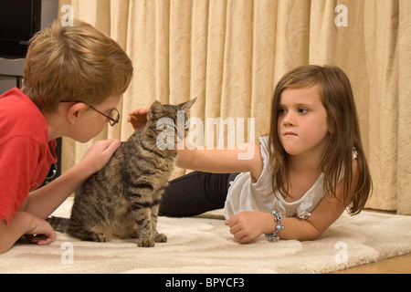 Two children at home playing with their pet cat