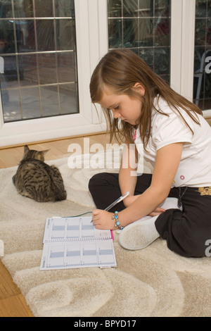 A left handed 8 year old girl writes notes in her school diary Stock Photo