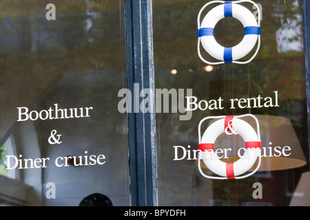 Amsterdam Shop window advertising boat rental, rentals and dinner cruise, cruises. On a corner of the Prinsengracht Canal. Stock Photo