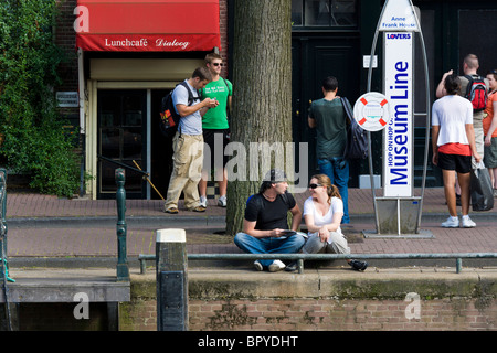 Amsterdam Museum Line Hop On canal cruise tour boat stop in front of the Anne Frank House front door, with people waiting. Stock Photo