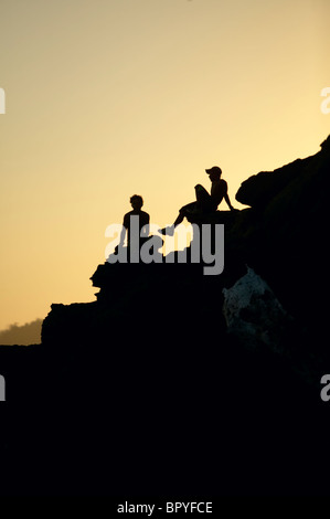 Silhouette of two boys sitting on rocks in Costa Rica. Stock Photo