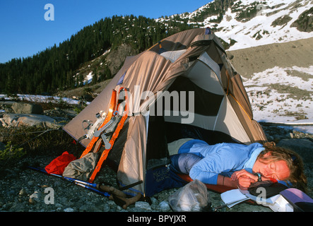 Woman sleeping in tent below snow covered mountain, British Columbia, Canada. Stock Photo