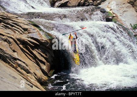 A man goes over a waterfall in a kayak. Stock Photo