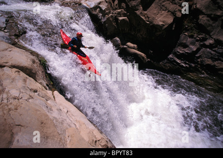 A man goes over a waterfall in a kayak Stock Photo