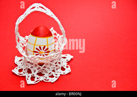Easter egg in white crochet basket isolated on red, landscape Stock Photo