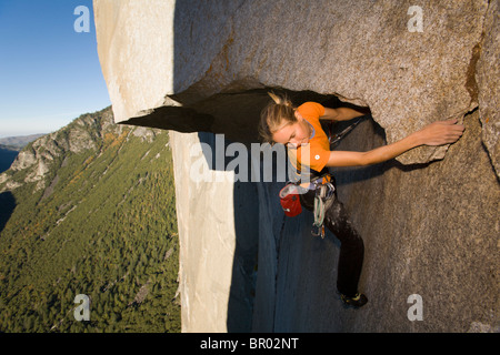 A female rock climber free climbs a granite big wall route in Yosemite National Park. Stock Photo