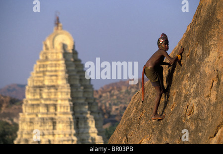 A young Indian boy dressed as a monkey bouldering. Stock Photo