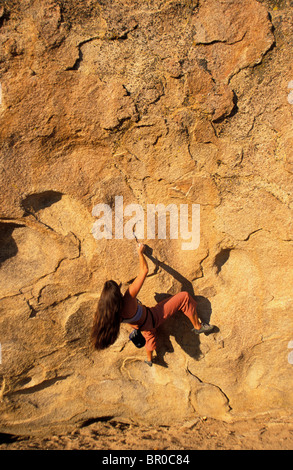 A female rock climber bouldering on an overhanging bouldering route in the desert. Stock Photo