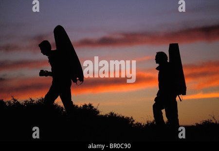 Two male rock climbers hike into a bouldering area at sunrise with their crash pads. Stock Photo