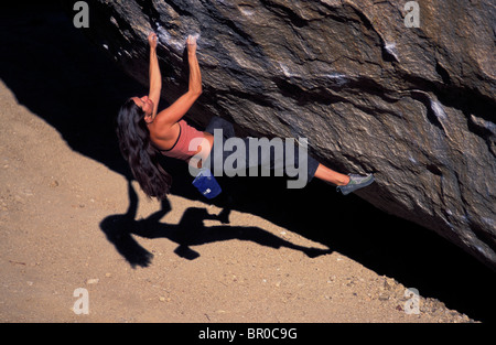 A female rock climber climbing on an overhanging bouldering route in the desert. Stock Photo