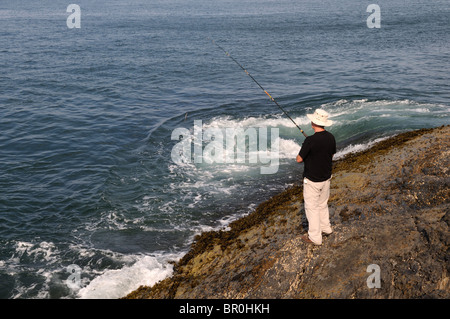 Man fishing off rocks near Mwnt Cardigan Bay Coastal Path Ceredigion Wales Cymru UK GB Stock Photo