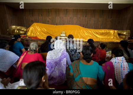 Pilgrims worshiping the statue of the sleeping Buddha, Mahaparinirvana Temple, Kushinagar, Uttar Pradesh, India. Stock Photo