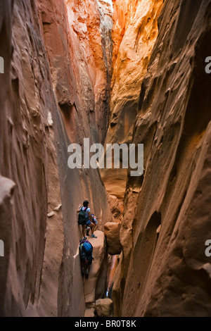 Three people in a slot canyon, Utah. Stock Photo