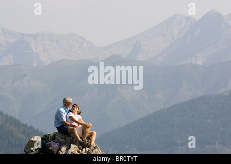 Mid-aged couple enjoy view from peak of a mountain in the Lizard Range near Fernie, British Columbia. Stock Photo