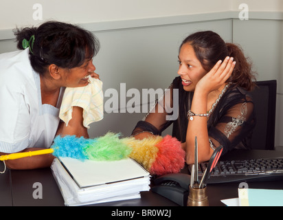 Cleaning woman and secretary talking gossip in the office Stock Photo