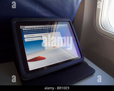Apple iPad on airliner tray table with screen displaying wifi login page. Stock Photo