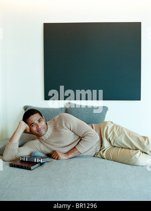 Man laying on bed with books Stock Photo