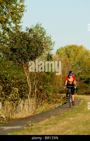 A woman is road cycling atsunset at Iona Beach, Richmond, British Columbia, Canada. Stock Photo