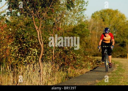 A woman is road cycling atsunset at Iona Beach, Richmond, British Columbia, Canada. Stock Photo