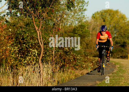 A woman is road cycling atsunset at Iona Beach, Richmond, British Columbia, Canada. Stock Photo