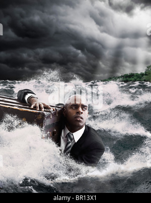 African American businessman in ocean holding trunk Stock Photo