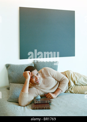 Man laying on bed with books Stock Photo