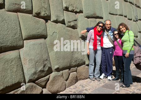 Tourists pose by the famous 12 sided stone, Calle Triunfo, Plaza de Armas,Cusco, Peru. Stock Photo