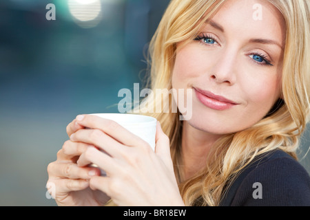 https://l450v.alamy.com/450v/br18ew/a-beautiful-smiling-young-woman-with-blond-hair-and-blue-eyes-drinking-br18ew.jpg