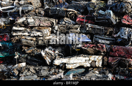 A large pile of crushed scrap cars await collection on the dockside before they are recycled. Stock Photo